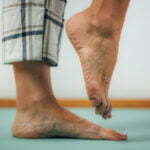 Photo des pieds et tibias d'une personne en pyjama se tenant sur un pied