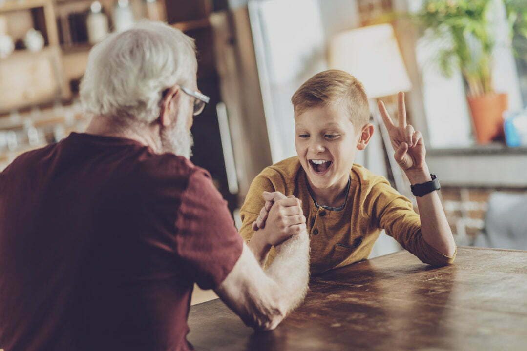 Photo d'un grand-père et d'un garçon faisant un bras de fer en souriant